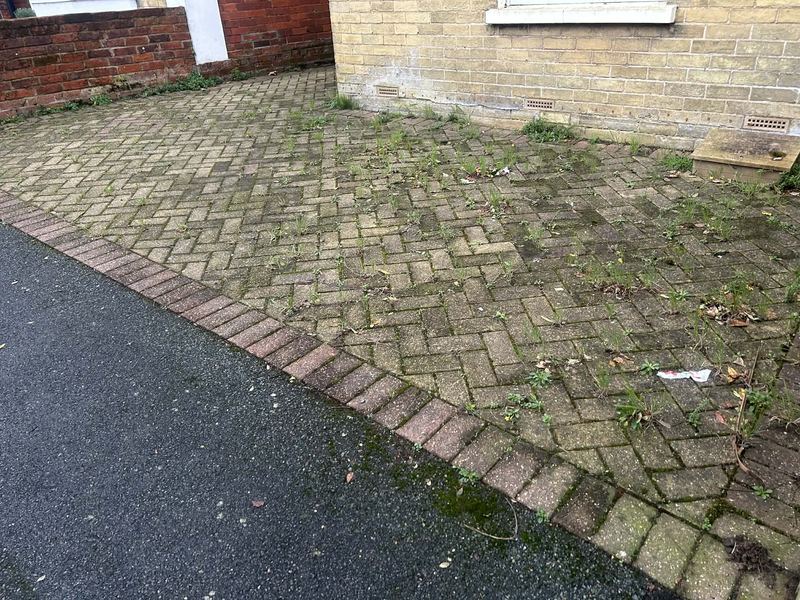 Herringbone driveway before pressure washing, covered in weeds, Isle of Wight