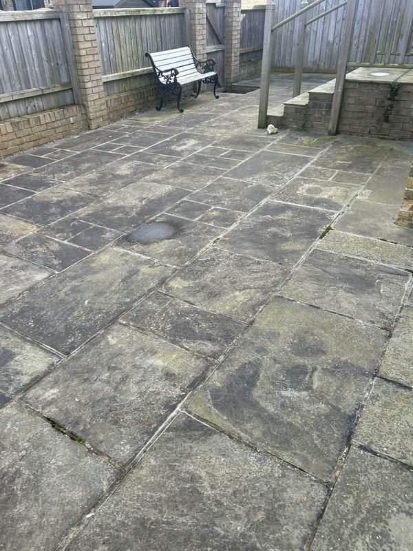 Slate patio before pressure washing, blackened with lichen, Isle of Wight